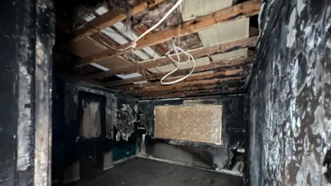 A room so badly damaged by fire the walls and floor are all charcoal black