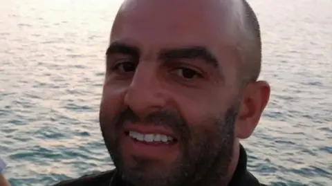 LNER Samir Zitouni is smiling at the camera in a close-up shot of his face. he is balding and has a moutache and a beard