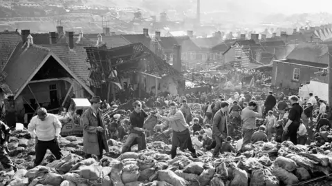 Getty Images Rescue workers bagging and moving some of the coal spoil following the catastrophic collapse of a colliery spoil tip in the Welsh village of Aberfan, near Merthyr Tydfil, on 21 October 1966