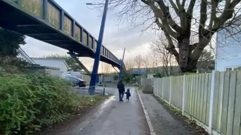 Two people walk past a bridge