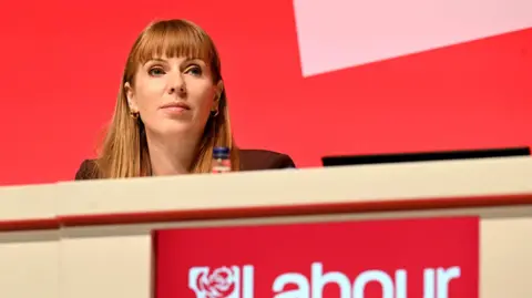 Angela Rayner sits behind a table on the podium at Labour's party conference last month.