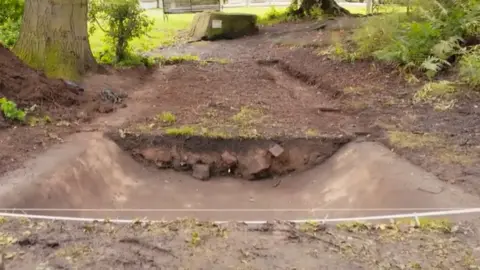 Part of a skatepark, covered in dirt and dust, having been dug up during an archaeological dig