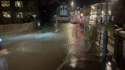 Ben Thomas A flood-covered road bridge in the dark.