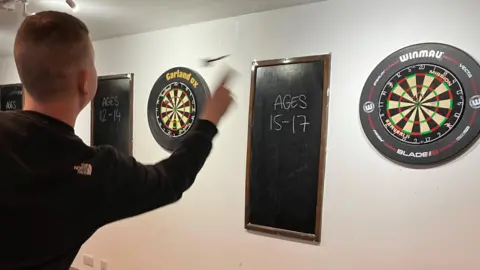 BBC Teenager throwing a dart at dartboard 