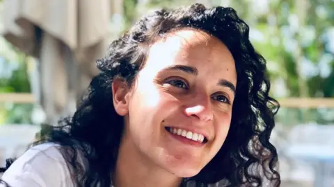 PA Media Handout photo of Emily Damari smiling. She has curly black hair and is wearing a white top