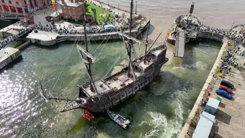 Jason Marcus An aerial view of the 160ft (48m) galleon which has six decks. Made from iroko and pine, its seven sails measure nearly 1,000 square metres. There are crowds of people surrounding the ship as it is moored at Liverpool's Royal Albert Dock.