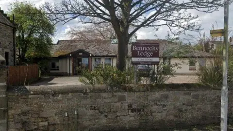 Bennochy Lodge is a low level building which sits behind a wall.