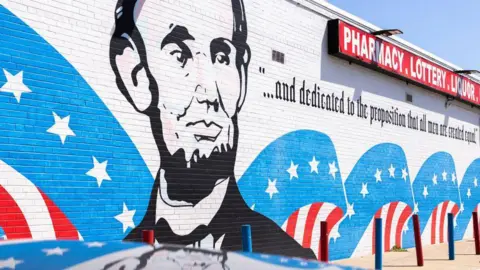 Getty Images The face of Abraham Lincoln is painted in black on the wall of a liquor store in Oak Park, Michigan. It is the main feature of a huge mural which has the colours of the USA flag - red, white and blue - emblazoned alongside the former US president. The words "and dedicated to the proposition that all men are created equal" is written under the red sign of the shop, taken from Lincoln's second inaugural address.