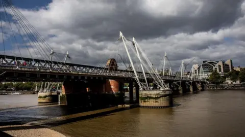 Getty Images Hungerford Bridge seen under patchy grey clouds from the south bank of the Thames with Charing Cross station in the distance