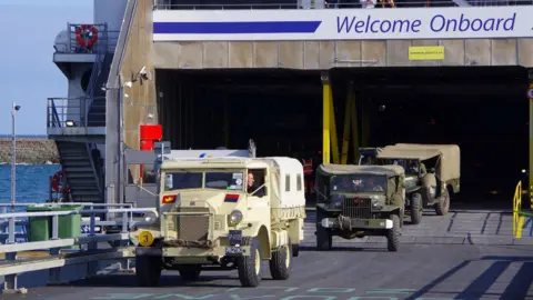 Brittany Ferries Three military vehicles, including a troop carrier and Jeeps, driving off a ferry ship.