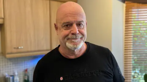 Joe Manning standing in a kitchen wearing a black T-shirt