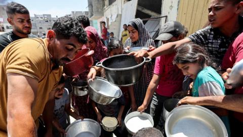 Palestinians wait to receive food at a charity kitchen in Khan Younis, in the southern Gaza Strip (30 May 2024)