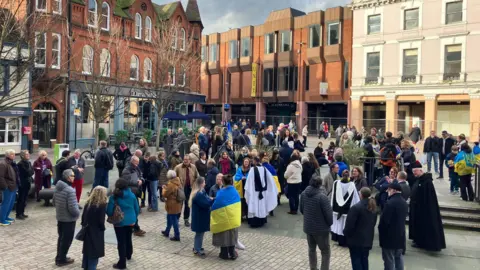 Jon Wright/BBC A crowd of people on Ipswich Cornhill, some have Ukrainian flags around their shoulders