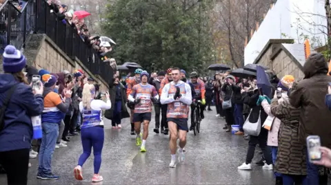 Danny Lawson/PA Kevin Sinfield thanks supporters lining the streets in the rain, cheering on his running challenge. 