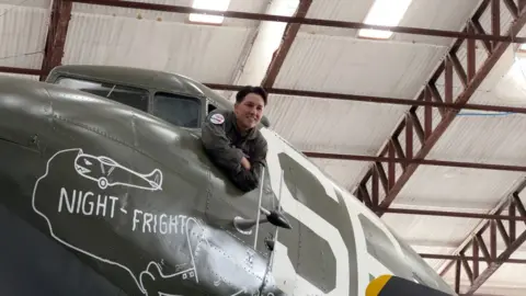 One of the US air crew leans out of the plane's cockpit window to have her photograph taken.