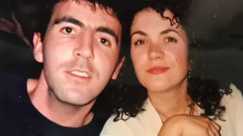 Liam Walsh, wearing a black jumper, and Alison Bell, wearing a white shirt, face the camera