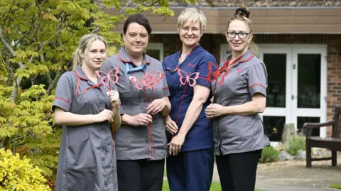 Myton Hospices Staff pictured with red metal butterflies