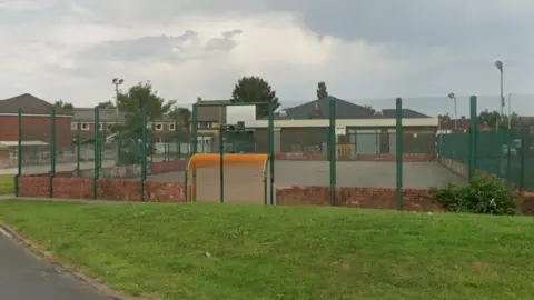 A down-trodden multi-use games area in Ribbleton, Preston, on a cloudy day.