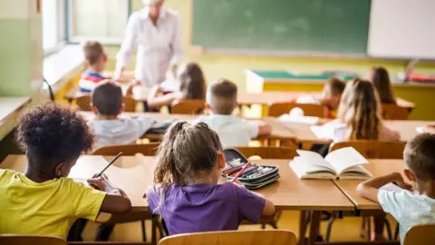 Rear view of elementary students attending a class in the classroom. - stock photo