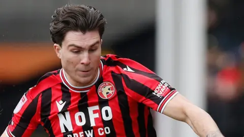 Mason Hancock in the centre of the picture competes to win the ball during a match for Walsall