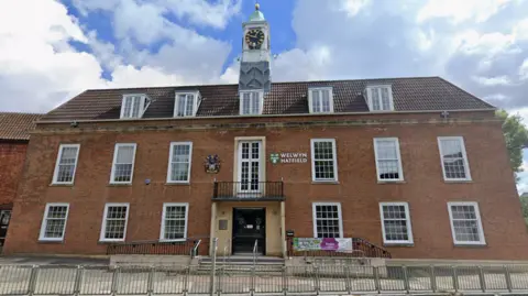 Welwyn Hatfield Borough Council The front of the brick-built Welwyn Hatfield Borough Council building, which has a clock tower in the middle of the roof. There are many long traditional windows and the council's name and crest are above the door.