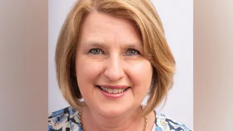 A headshot picture of Karen Titchener wearing a flowery top and smiling
