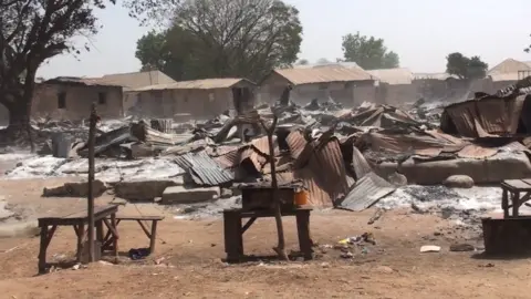 Burnt wooden stalls and corrugated iron from a market in the aftermath of an attack.