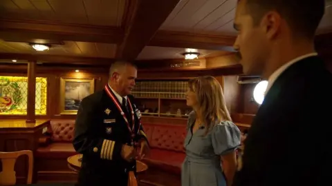 The commander and his executive assistant show me a luxurious room in the ship that has red leather seats, a stained glass window bearing the Peruvian coat of arms, polished wooden furniture and row of antique books