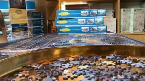 A side view of a large jigsaw puzzle, with many pieces waiting to be placed