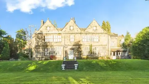 Holroyd's Estate Agents The back of the manor house with a rolling lawn and steps leading to a grand property