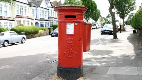 Red postbox on sunny street 