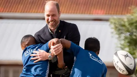 PA Media The Prince of Wales (centre) takes part in a rugby coaching session with local school children during a visit to Ocean View Secondary School in Cape Town, South Africa