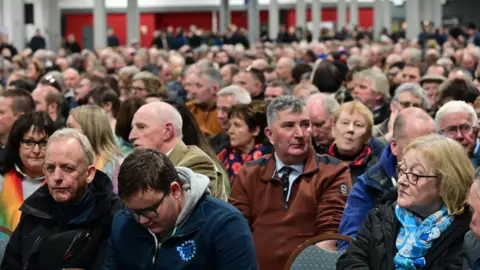 Pacemaker Hundreds of people sitting in rows of chairs in a large conference centre 