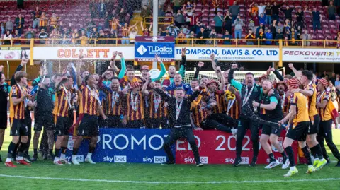 Bradford City team and managers on the pitch, hands in the air.