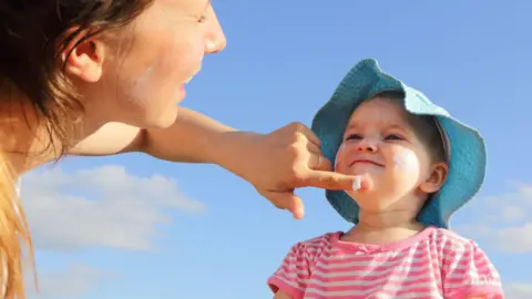 Getty Woman putting sunscreen on small child's face
