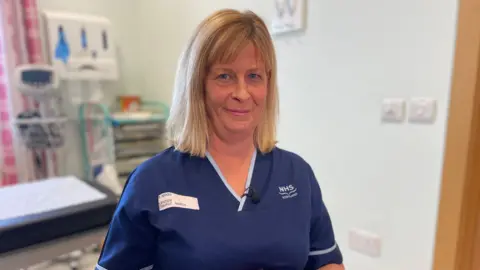 Head and shoulders image of Maureen Wood, a senior charge nurse at Ninewells Hospital's Assisted Conception Unit, looking straight at the camera. She has shoulder-length blonde hair and is wearing a navy nurses tunic.