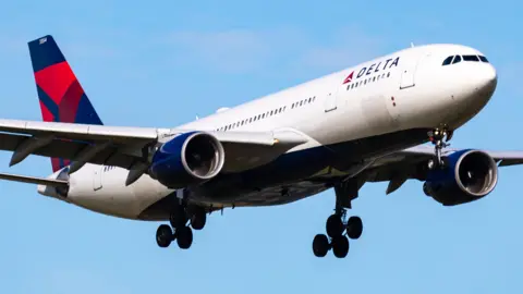 A Delta Air Lines Airbus A330-200 in flight with a blue sky background
