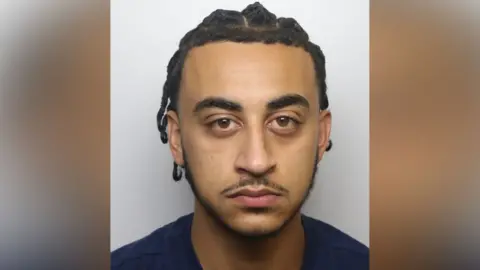 Thames Valley Police Custody photograph of a person with dark braided hair, shown from the shoulders up against a plain light background.