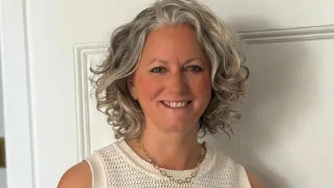 Tanya Hutson A smiley woman with curly hair looks at the camera. 