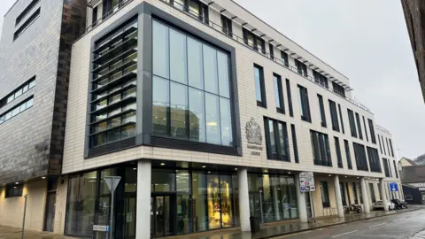 Exterior of the Mags court building with glass windows.