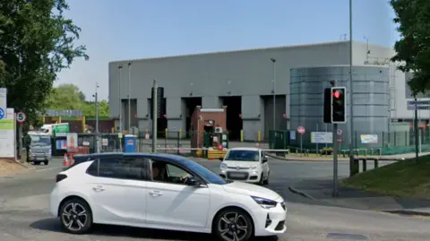 Image shows the entrance to a recycling centre in Gatley. A white car is driving in front of it. 