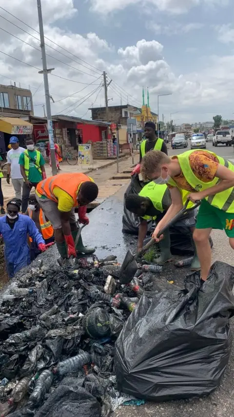 Buz Stop Boys UK volunteer is seen with a spade, joining local volunteers in cleaning a street