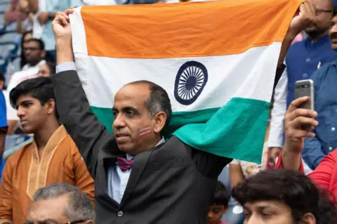 AFP Seorang pria mengangkat bendera India sebagai Presiden AS Donald Trump dan Perdana Menteri India Narendra Modi hadir "Howdy, Modi!" di NRG Stadium di Houston, Texas, 22 September 2019. -