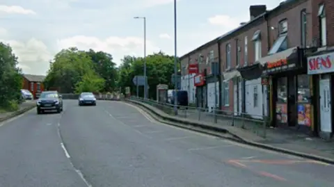 Google A street view image of Hyde Road. There are cars on the road and there is a line of takeaways on the side of the street.