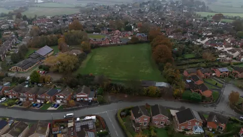 Aerial view of a field in Bayston Hill surrounded by housing