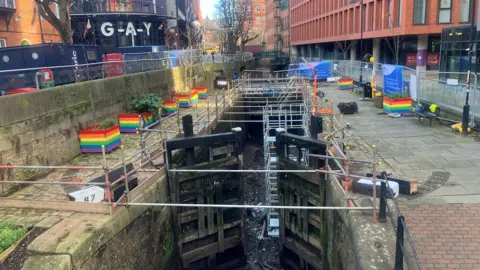 Photograph of the Rochdale Canal in Manchester's Gay Village. The image shows the water drained from the canal and scaffolding in place to allow the construction work to go ahead.