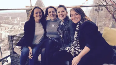 Family photo Four women on garden bar furniture above a skyline in a sky bar