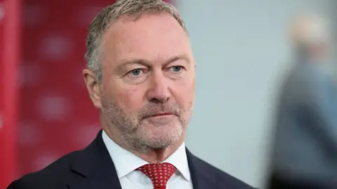 Communities Secretary Steve Reed wears a dark suit with a white suit and a red tie