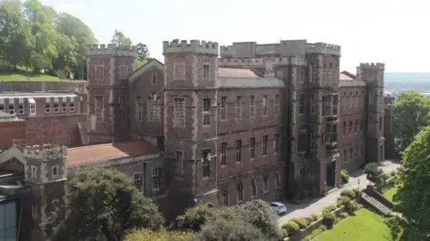 Queen Elizabth Hospital school, which looks like a castle surrounded by trees and grass grounds.