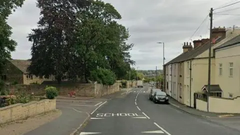 Netherton Lane and Netherton Hall Drive in Wakefield with cream buildings on the right and left, and a large tree on the left